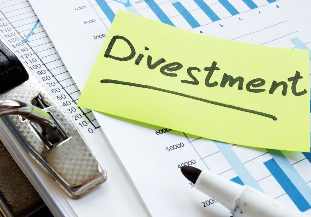 A lime green sticky note with the word "Divestment" handwritten on it