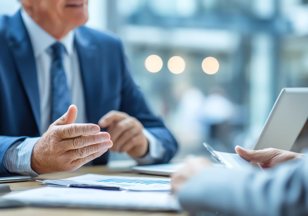 A close-up of a businessman in a blue suit gesturing with his hands during a professional meeting