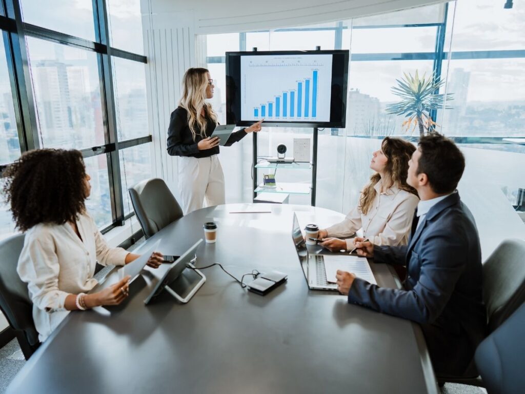 A young woman leads a business presentation in a bright, modern office