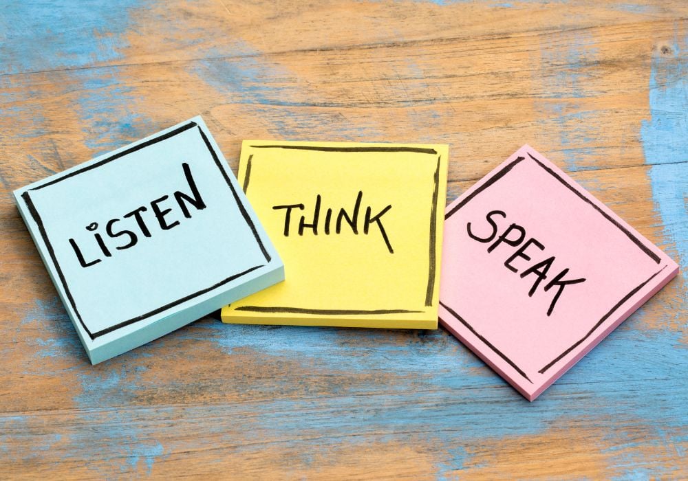 Three colourful sticky notes—blue, yellow, and pink—arranged in a row on a rustic wooden surface