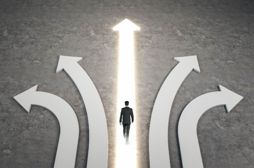 An overhead view of a businessman walking along a glowing white arrow pointing straight ahead