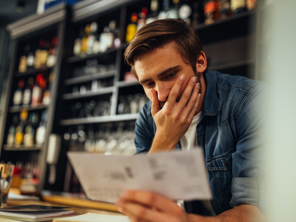 A young man in a denim shirt looks distressed and worried