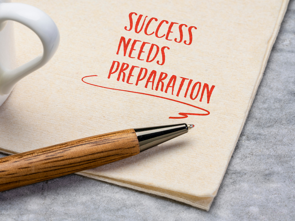A close-up of a beige napkin with the motivational phrase "SUCCESS NEEDS PREPARATION" written in red ink
