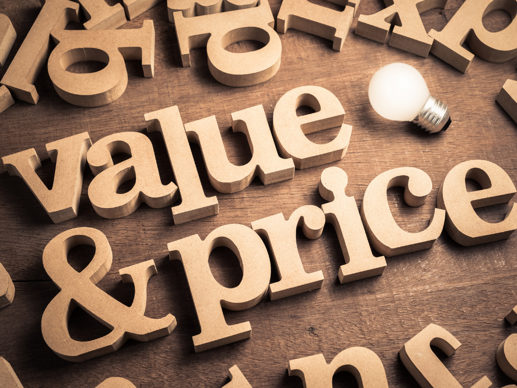 Large wooden letters spelling "value & price" on a rustic wood surface
